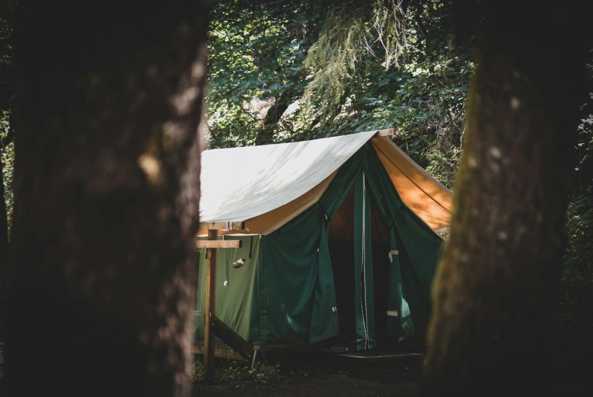 Emergency survival tent pitched in a harsh wilderness under darkening skies.A rugged orange survival tent pitched on a windy hillside at dusk, storm clouds rolling in.